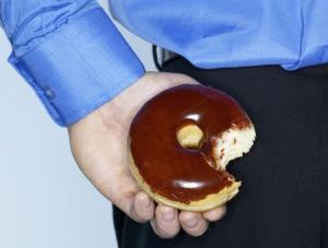 Young man hiding doughnut --- Image by © Nation Wong/zefa/Corbis